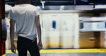 A bottle of Scatter Slip in the back pocket of someone standing on a subway platform as a train passes